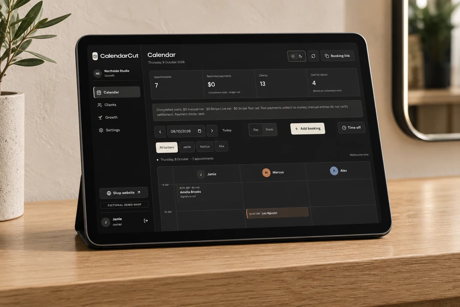 Tablet displaying CalendarCut's sample appointment diary in dark mode on an oak counter